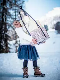 Enfant portant des cadeaux dans un paysage enneigé en montagne