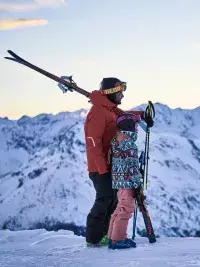 Parent et enfant en ski au lever du soleil lors de First Tracks aux Arcs