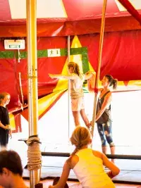 Des enfants s'initient à l'équilibre sur un fil sous un chapiteau de cirque aux Arcs, encadrés par une animatrice