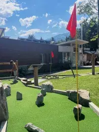 Children playing outdoor mini-golf at a mountain resort in summer