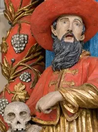 Statue religieuse polychrome représentant un homme barbu vêtu de rouge, tenant un livre et un crâne.