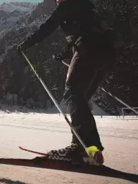 Une fondeuse pratique le pas de patineur sur une piste de skating traversant les alpages enneigés des Arcs en Savoie, face aux sommets