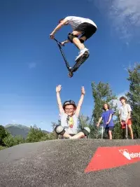 Enfant en trottinette faisant un saut sur pumptrack aux Arcs