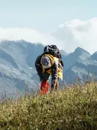 Participant ramassant des déchets en montagne face aux sommets.