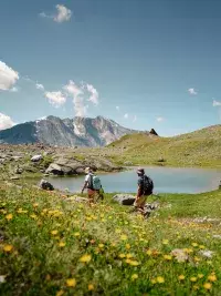 Randonneurs autour d’un lac de montagne fleuri.