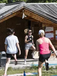 Un groupe de participants effectue des mouvements de cardio dynamiques lors d'une séance de fitness en plein air aux Arcs, sous la direction d'un animateur énergique