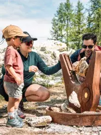 Famille découvrant une installation artistique en montagne.