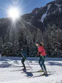 Une skieuse de fond profite du grand air et de l'espace sur une large piste damée pour le skating dans la vallée de la Tarentaise