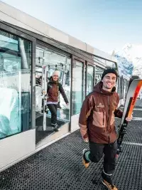 Skiërs die uit de kabeltrein stappen met ski’s in de hand