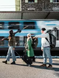 Skieurs marchant avec leurs skis devant un train en gare
