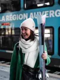 Skieuse avec skis devant un train régional en gare