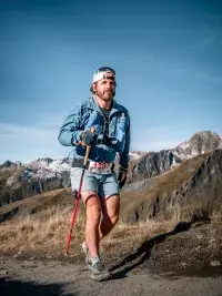 Un trailer court en descente sur un sentier serpentant vers la vallée de Bourg-Saint-Maurice, avec les montagnes alpines en arrière-plan sous un ciel dégagé