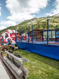 Vue d'ensemble de l'aire de jeux estivale à Arc 2000 incluant trampolines, châteaux gonflables et espaces de détente en Savoie